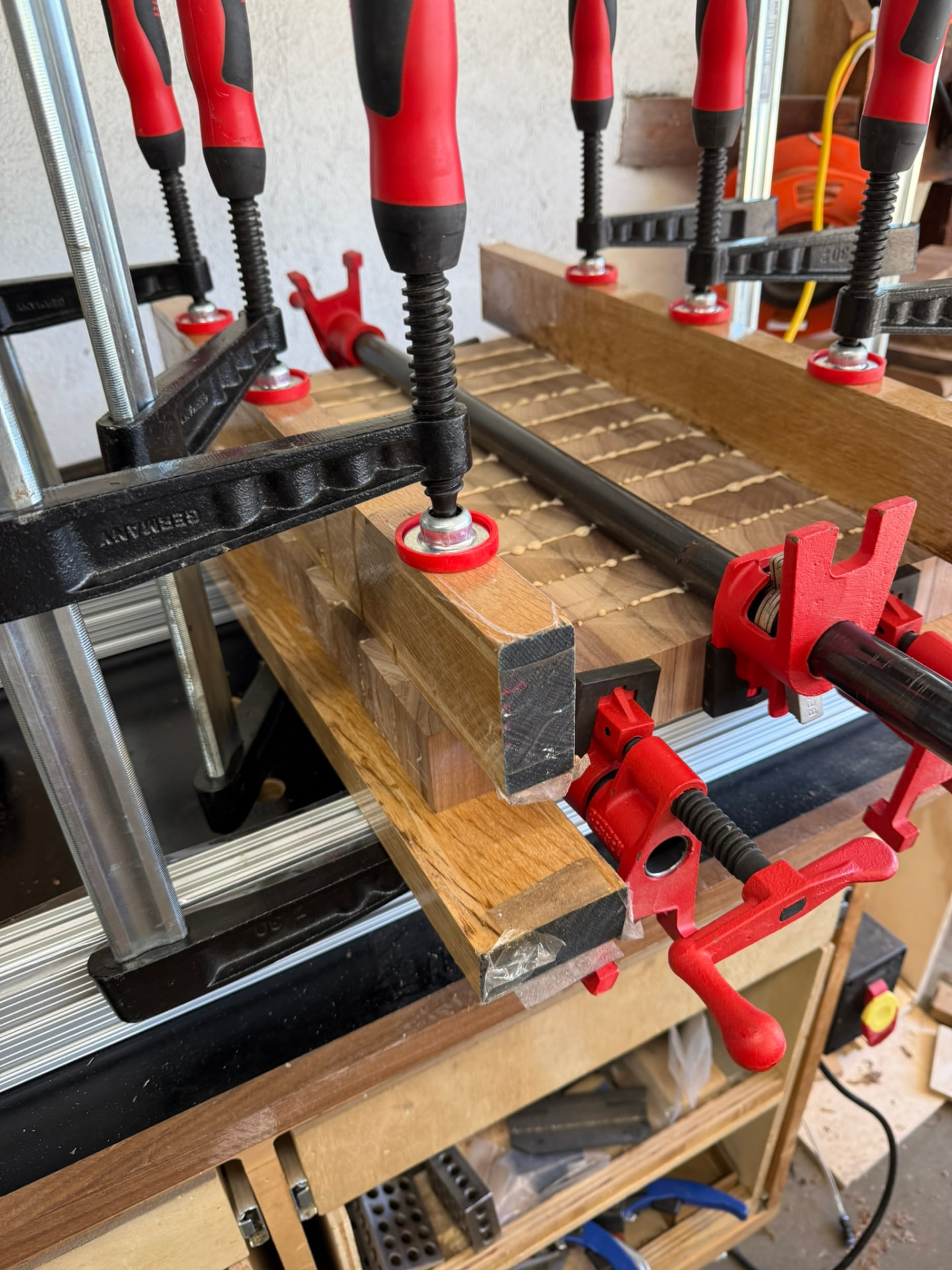 A board glue-up clamped on the bench, glue beads still visible between the blocks